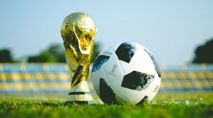 Football ball and cup on the green pitch